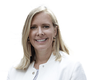 A smiling woman with blonde hair wearing a white jacket, earrings, and glasses.